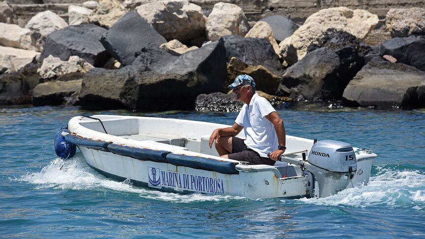 Homme sur un bateau équipé d’un moteur BF15 en zone côtière. 