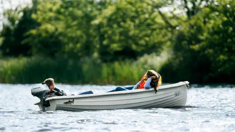 Deux personnes allongées dans un bateau sur l'eau avec un moteur Honda.