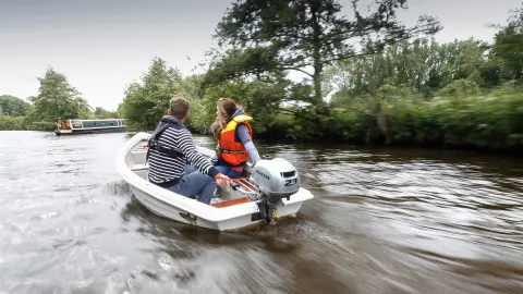 Deux personnes à bord d’un bateau utilisant le moteur BF2.3, à côté d’un bateau-mouche.