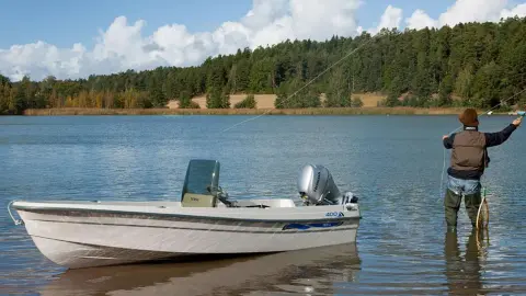 Mannequin pêchant sur un lac avec un bateau à proximité mettant en valeur le moteur BF8-10.