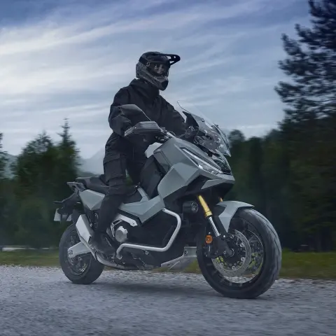 Vue de face ¾ du X-ADV sur gravier avec le pilote debout