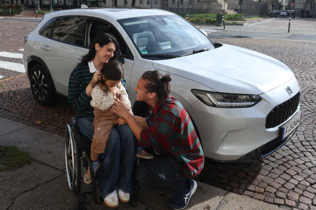 Femme en chaise roulante avec son enfant et son mari à côté d'un Honda ZR-V